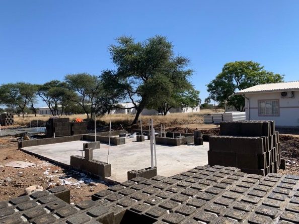 Betonfundament mit daneben gestapelten Bauelementen auf dem Klinikgelände in Okakarara