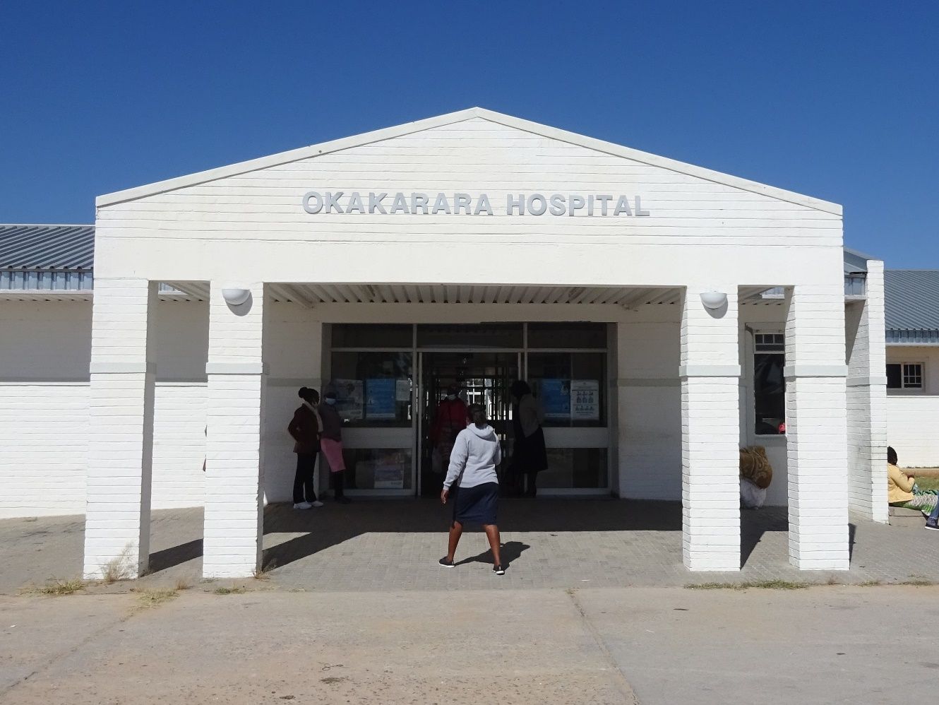 Eingang des Okakarara Hospital, ein weißes Gebäude mit Schriftzug über dem Portal